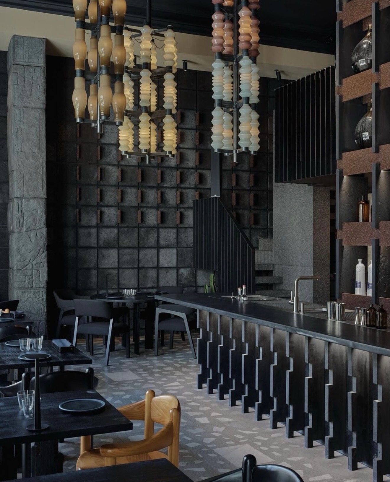 Bar- och restaurangdisk klädd i mörk sten, med hängande belysning och terrazzogolv